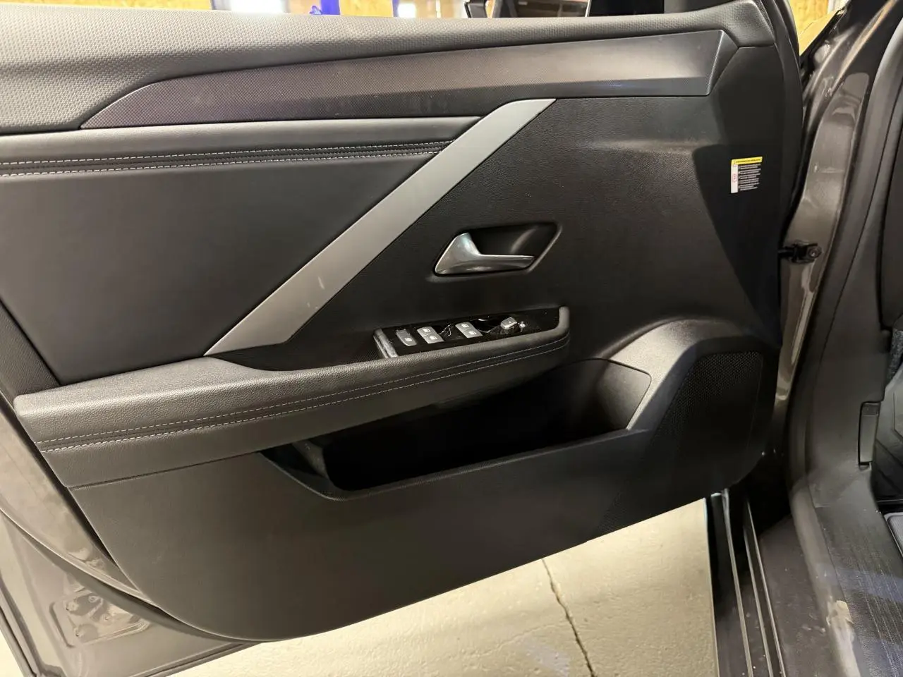 Gros plan sur la porte avant gauche gris foncé de l’Opel Astra 2024 avec commandes de vitres et poignée intégrée.