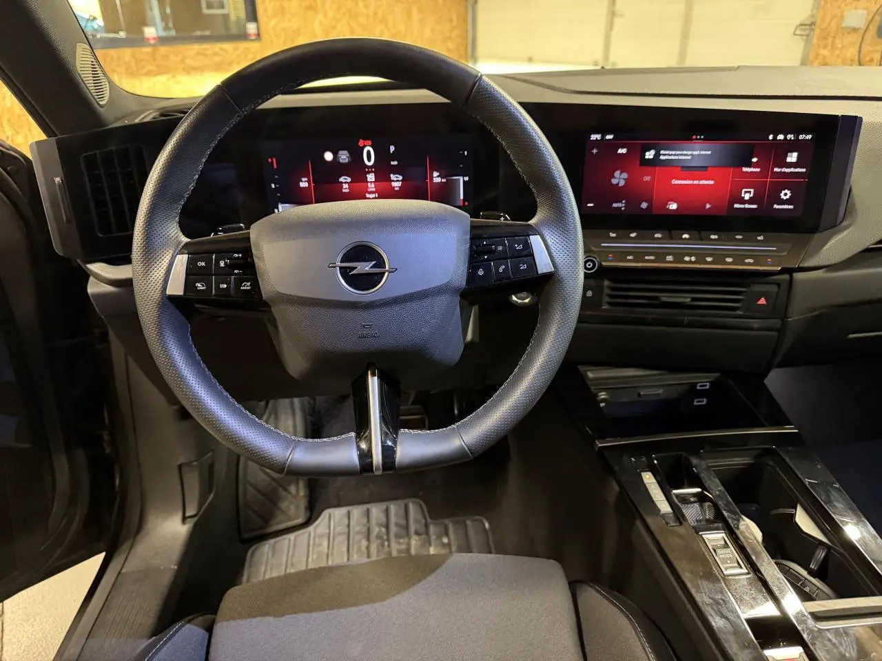 Vue intérieure de face du poste de conduite de l'Opel Astra 2024 avec volant cuir et écran tactile panoramique noir.