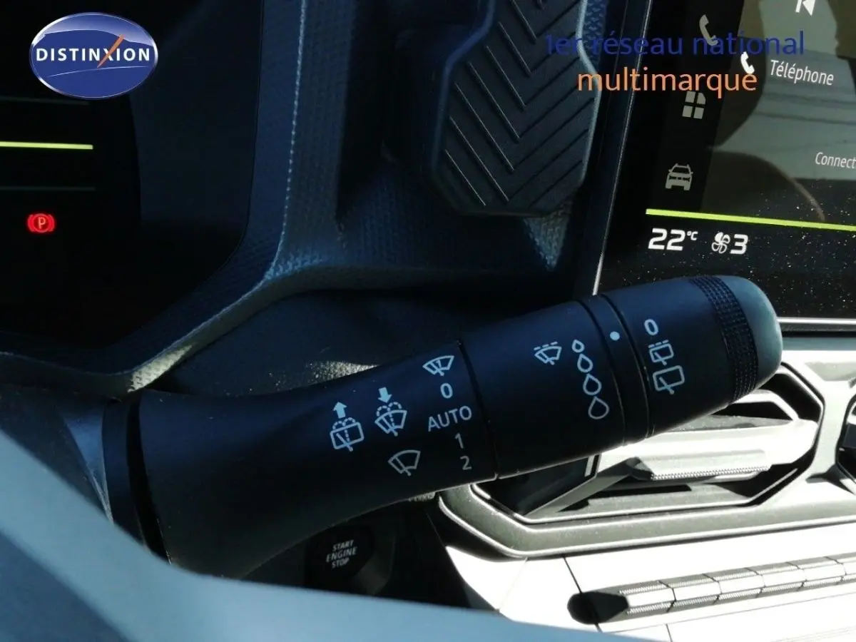 Gros plan sur la commande des essuie-glaces du Dacia Duster gris schiste métal, avec tableau de bord et écran tactile en arrière-plan.
