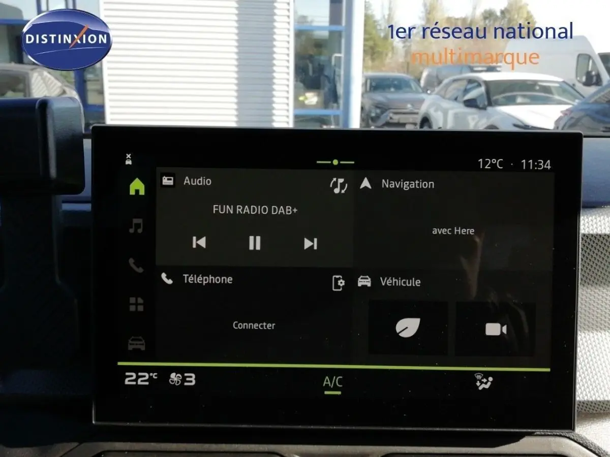 Écran tactile central du Dacia Duster gris schiste métal, affichant la radio et la navigation, vue intérieure frontale.