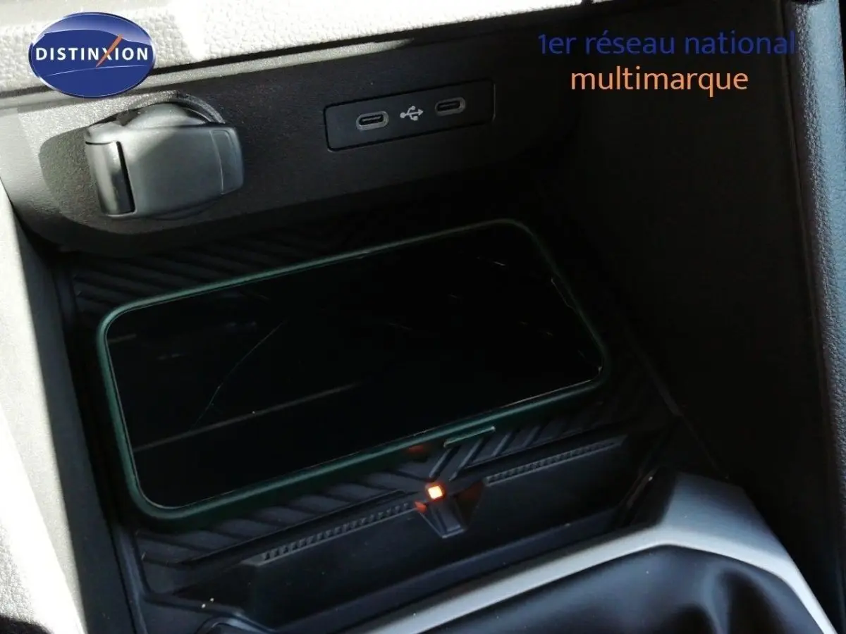 Gros plan sur la console centrale du Dacia Duster 2026, montrant un smartphone en charge sans fil et une prise USB.