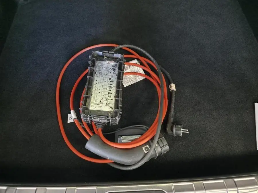 Câble de recharge hybride rechargeable Peugeot 408 2024 posé sur tapis noir dans le coffre du véhicule.