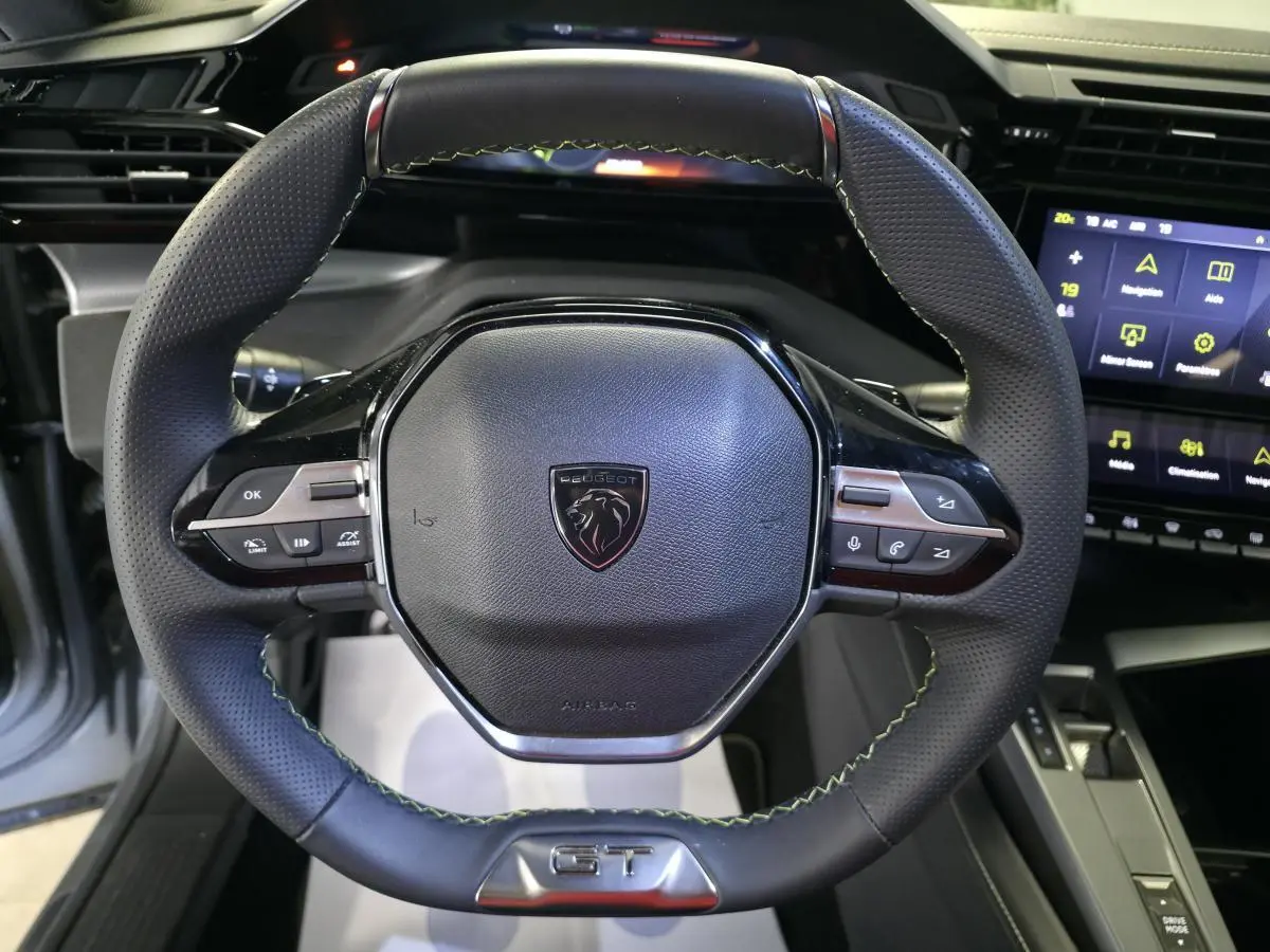 Volant cuir perforé noir avec surpiqûres vertes et logo GT, tableau de bord numérique et écran tactile Peugeot 408 2024.