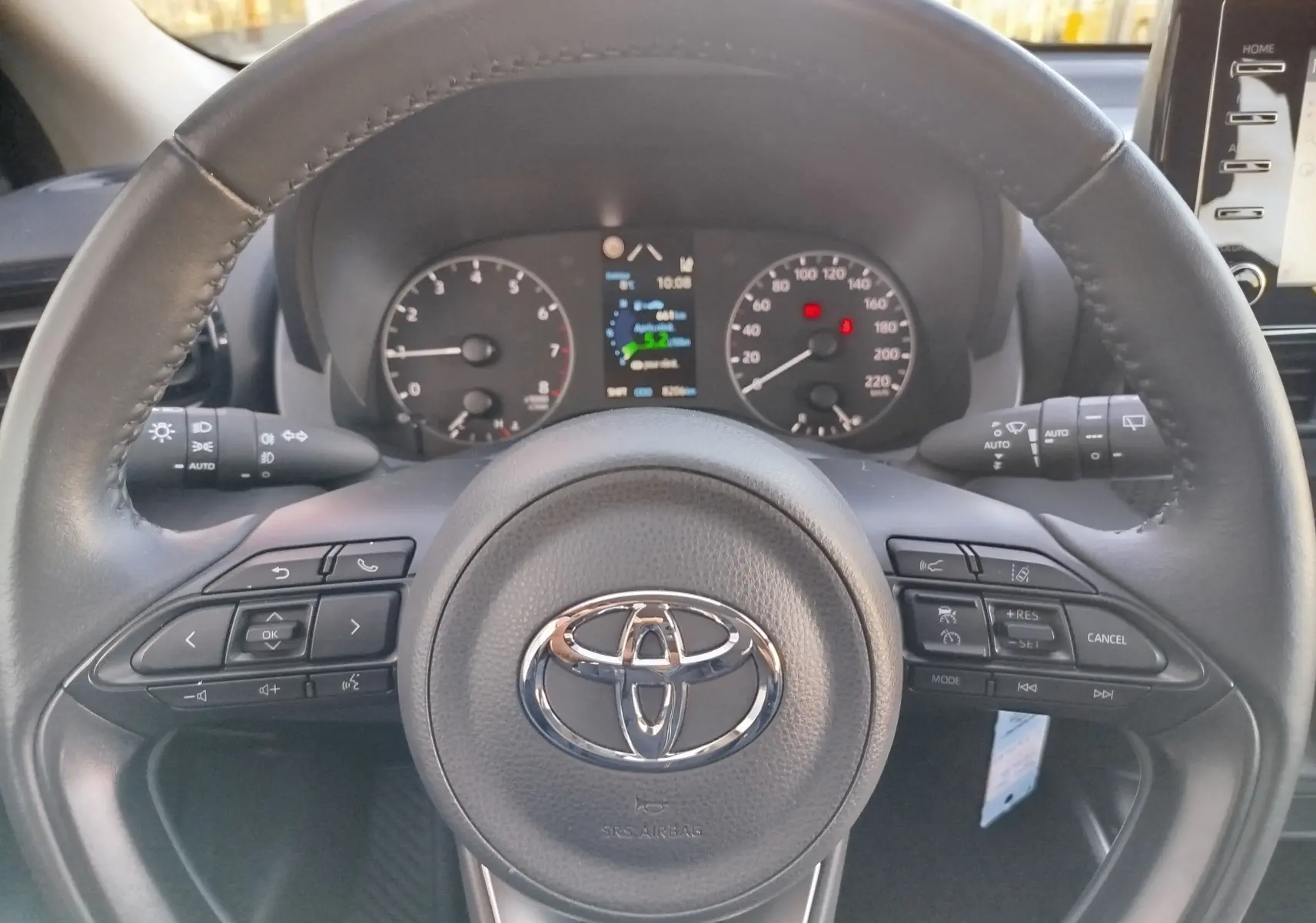 Vue rapprochée du volant noir de la Toyota Yaris 2023 avec commandes intégrées et tableau de bord digital.
