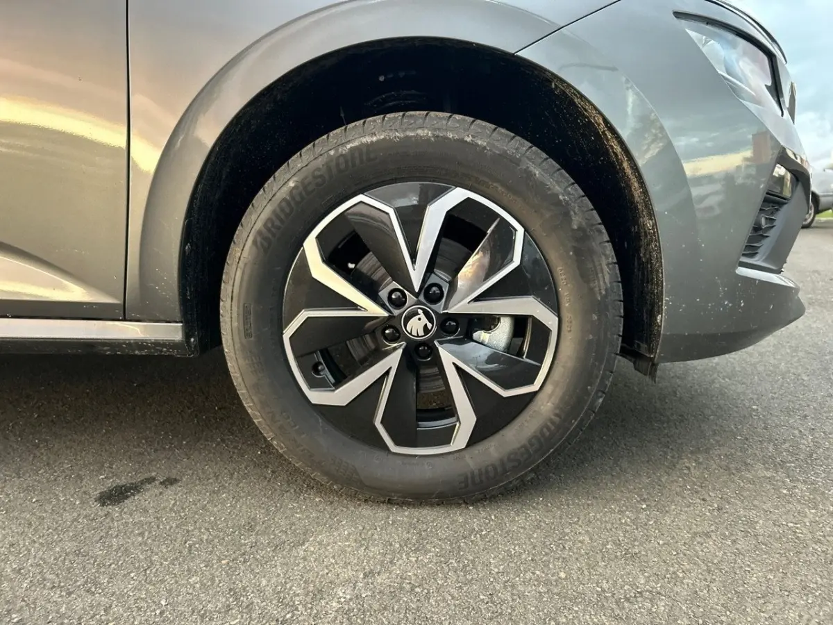 Gros plan sur la roue avant gauche gris clair d'un Skoda Kamiq 2025 avec jante alliage au design géométrique noir et argent.