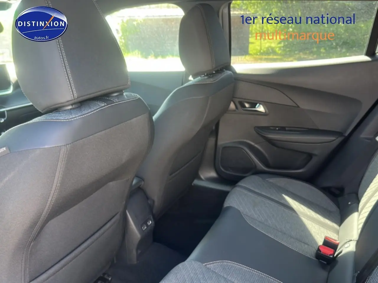 Vue intérieure arrière droite de la Peugeot 2008 1.2 100 Allure 2025, sièges tissu gris et noir avec coutures contrastées.