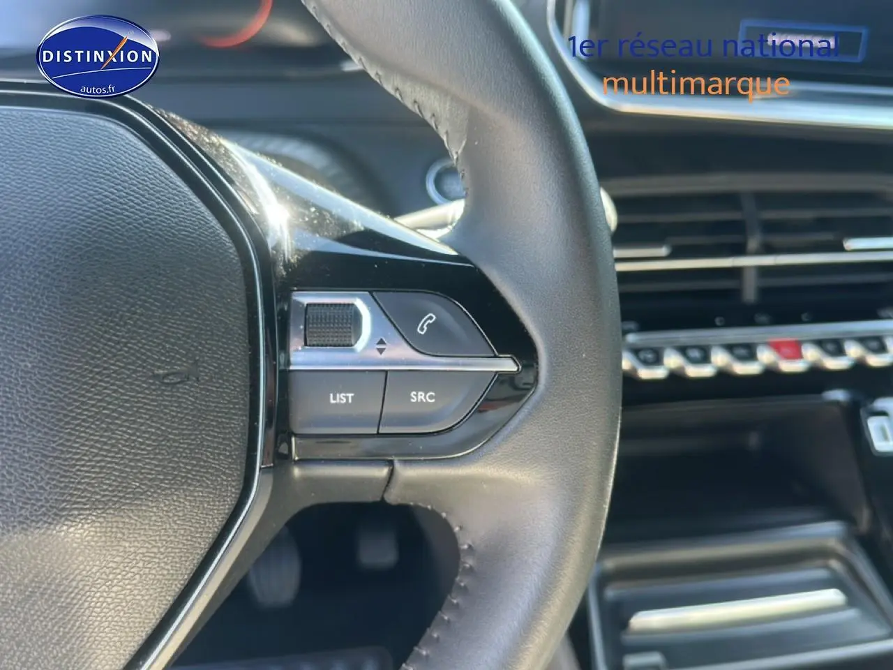 Gros plan sur le volant multifonction noir de la Peugeot 2008 1.2 100 Allure avec commandes audio et téléphone intégrées.