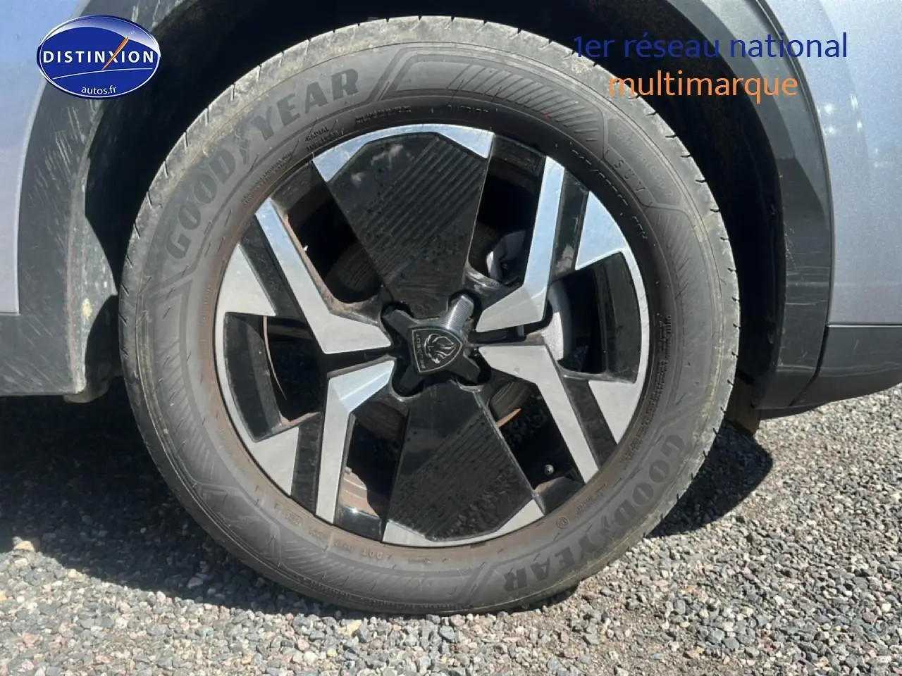 Gros plan sur la roue avant droite du Peugeot 2008 gris artense avec jante alu bicolore et logo lion central.