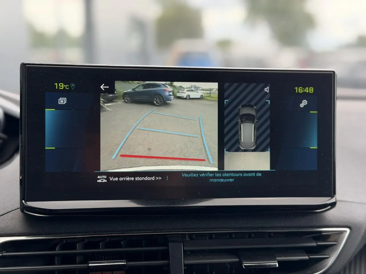 Écran tactile intérieur montrant la caméra de recul et l'aide au stationnement du Peugeot 3008 noir Perla, vue arrière.
