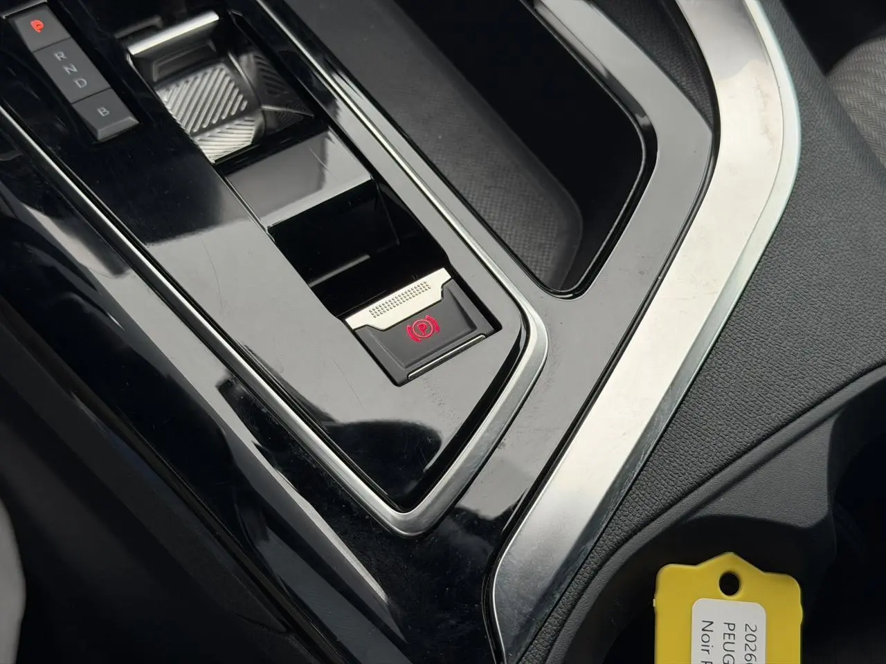 Gros plan sur la console centrale noire du Peugeot 3008 Plug-in Hybrid avec frein de stationnement électrique activé.