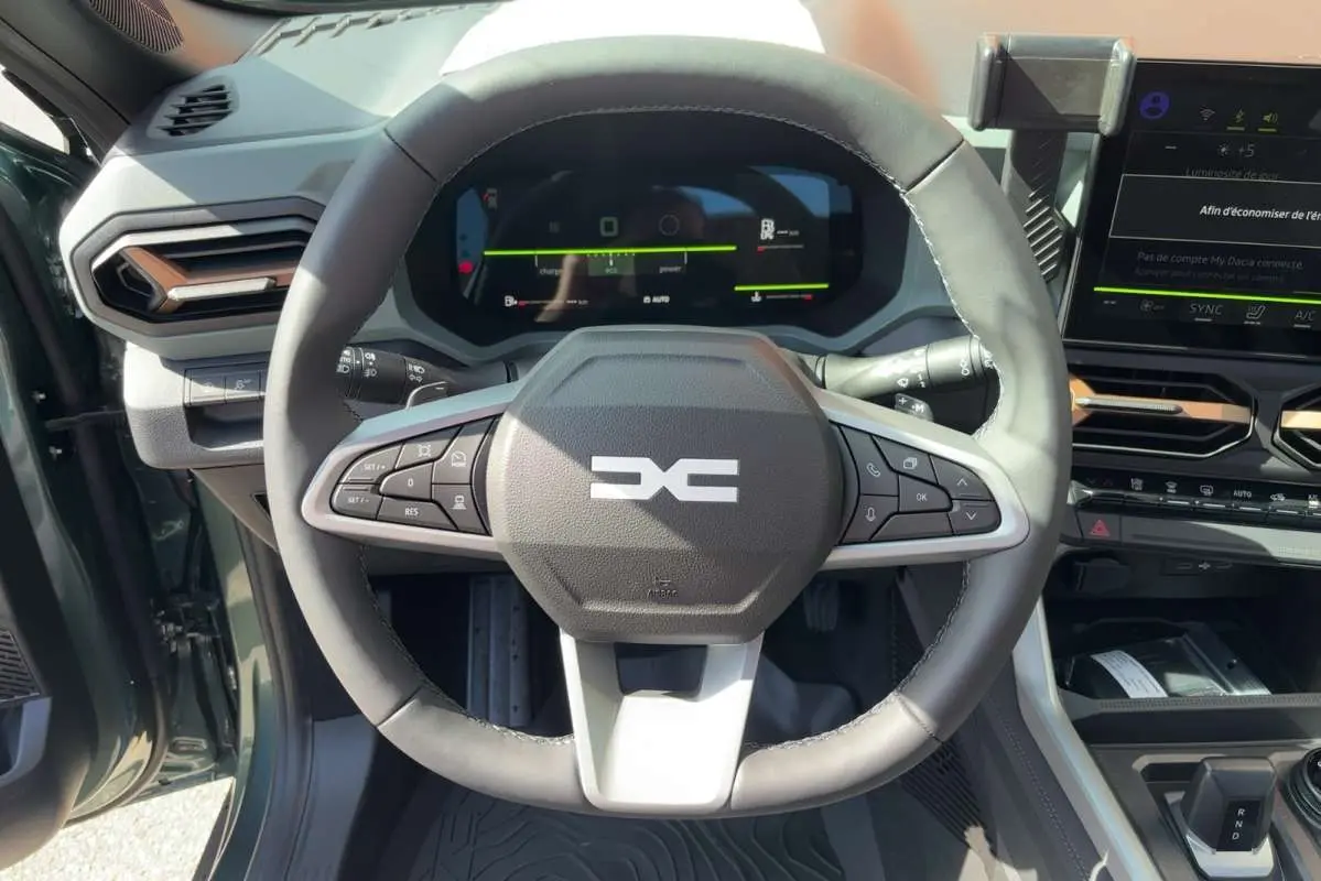 Vue intérieure centrée sur le volant cuir du Dacia Bigster vert cèdre avec tableau de bord digital et écran tactile.