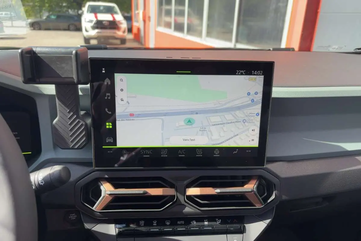 Vue intérieure du tableau de bord du Dacia Bigster Hybrid-G 150, écran tactile GPS et aérateurs hexagonaux noirs et bronze.