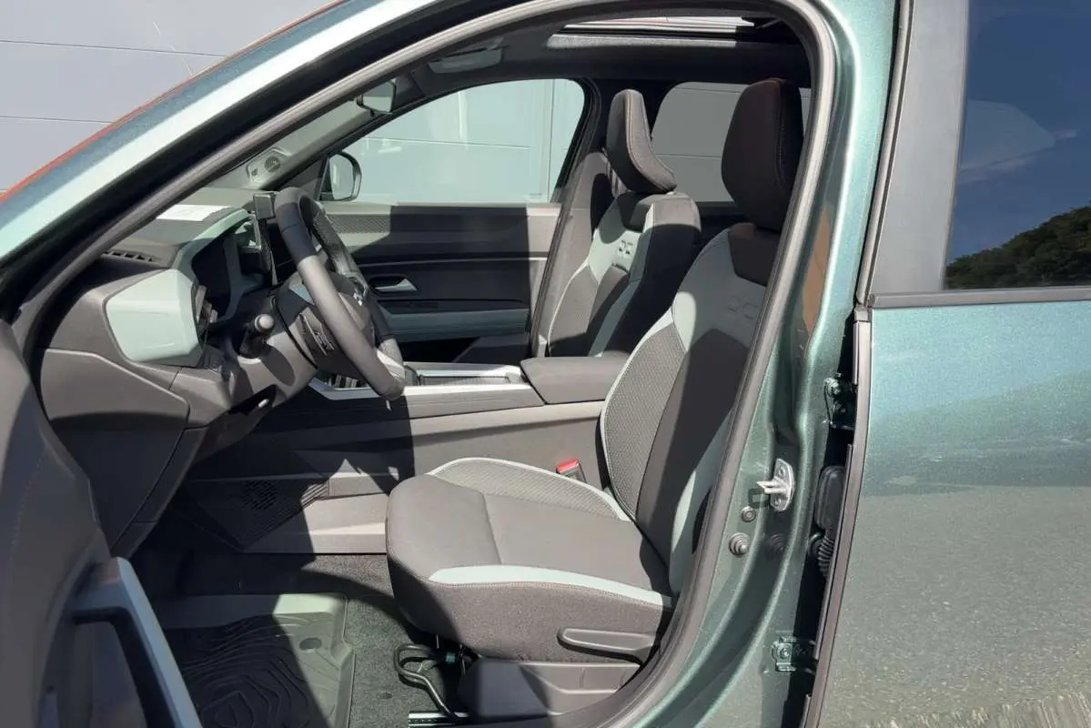 Vue intérieure côté conducteur du Dacia Bigster vert cèdre, montrant les sièges avant et le volant cuir soft feel.
