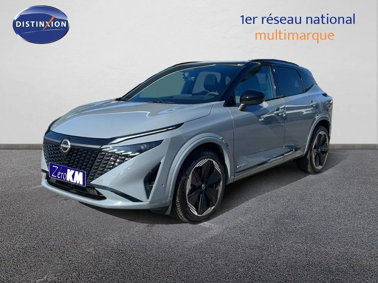 Nissan Qashqai gris céramique métal en 3/4 avant droit, avec jantes noires et toit panoramique visible.