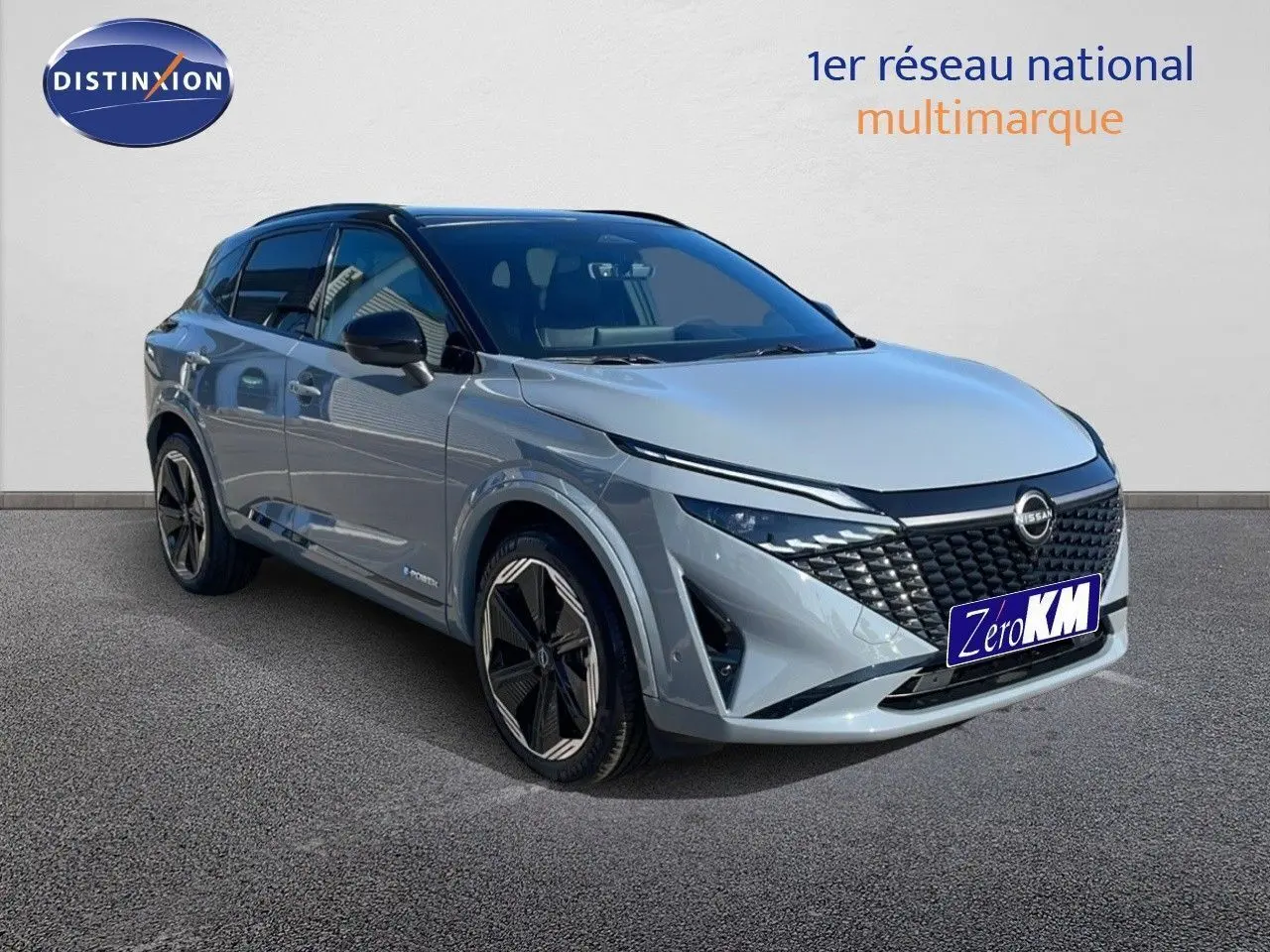 Vue de face du Nissan Qashqai gris céramique métal avec calandre noire et phares LED allumés dans un showroom.