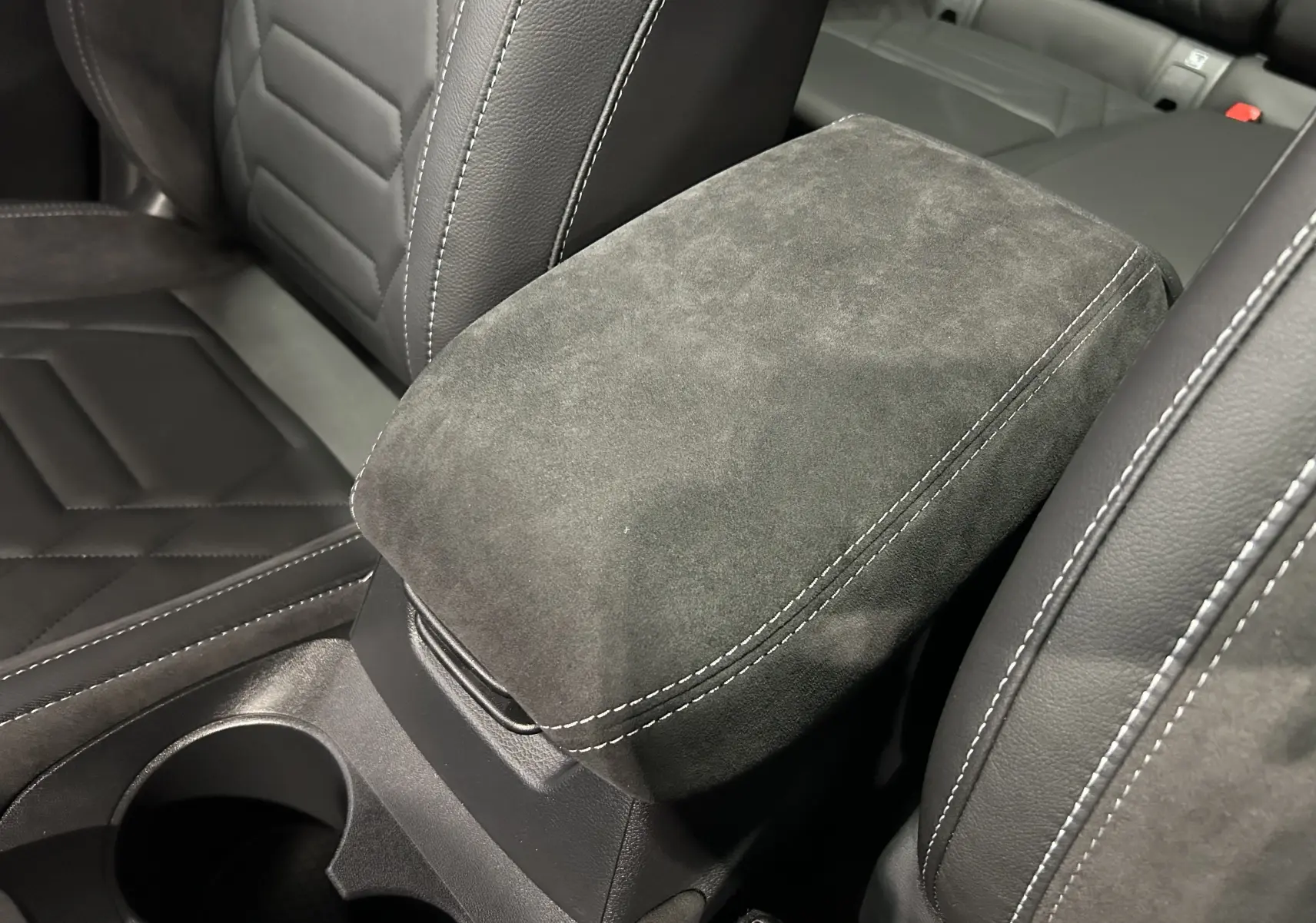 Gros plan sur l'accoudoir central en alcantara gris et les sièges en cuir noir du Nissan Qashqai 2025.