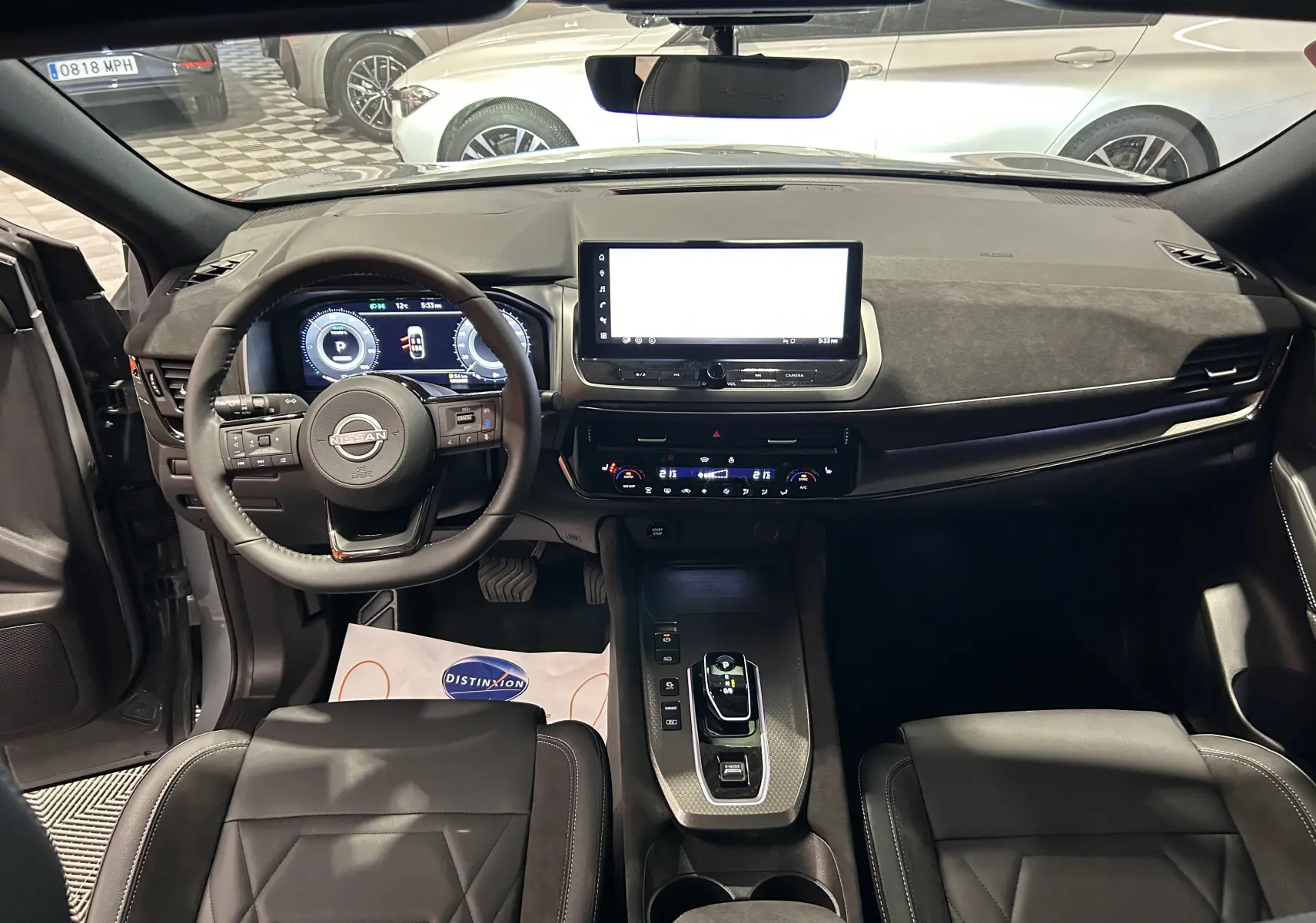 Intérieur du Nissan Qashqai 2025 vue de face, volant multifonction, écran tactile et sièges cuir noir visibles.