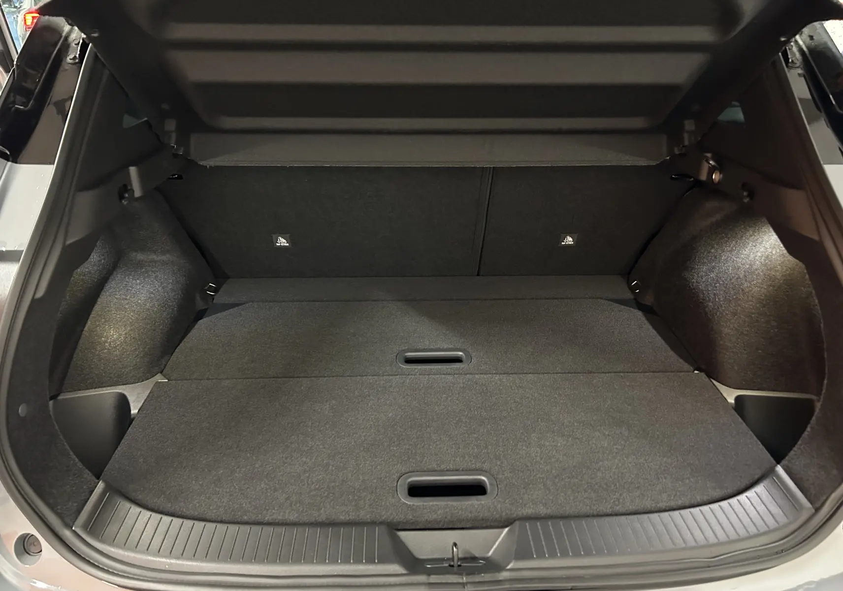 Coffre ouvert du Nissan Qashqai 2025 gris céramique, montrant un espace de chargement plat et bien fini.