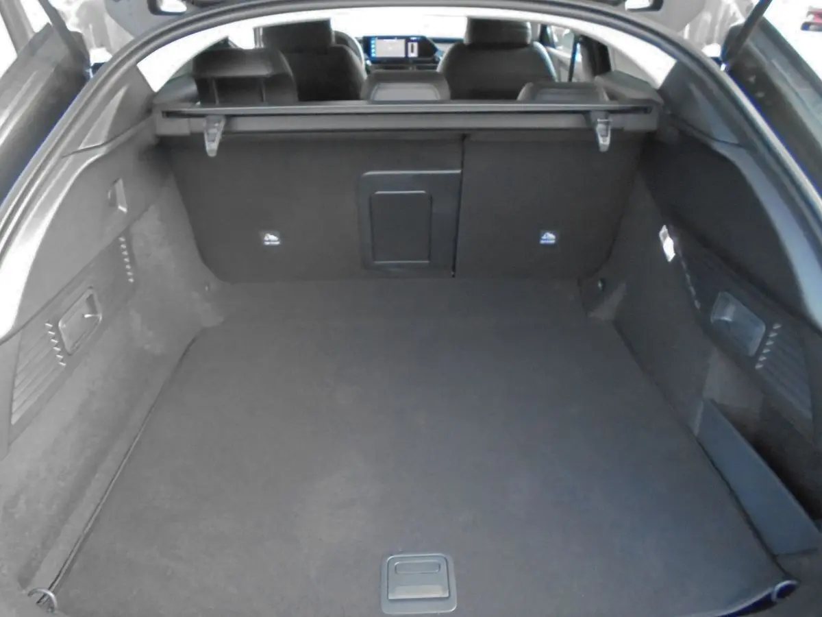 Coffre ouvert d’une Citroën C5 X gris platinum 2022, vue arrière montrant l’espace de chargement et la tablette cache-bagages.