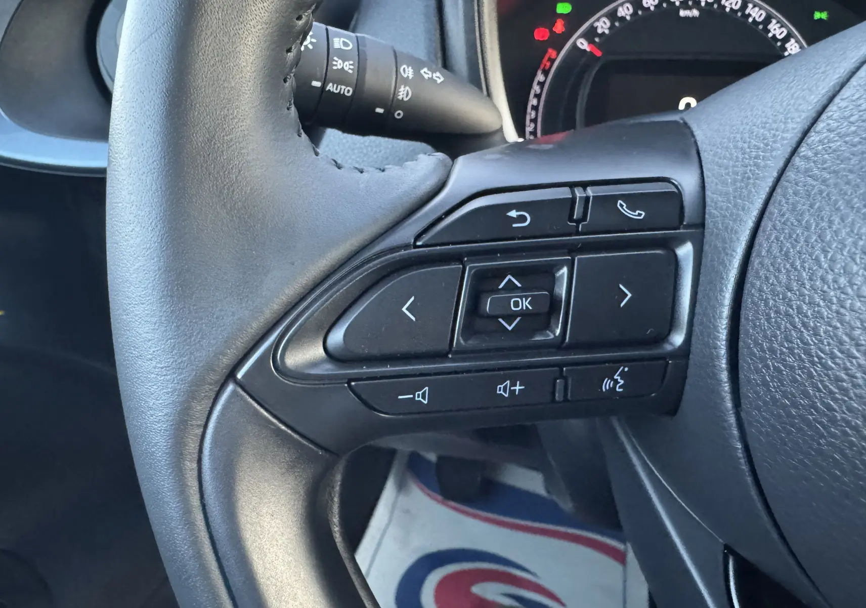 Gros plan sur les commandes au volant côté droit d'une Toyota Aygo X 2025, avec tableau de bord partiellement visible.