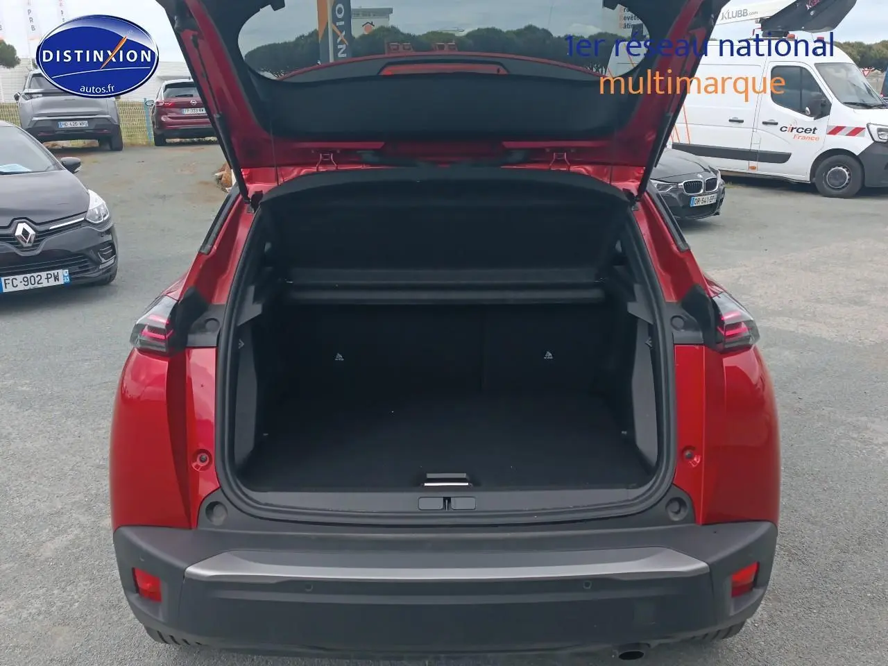 Coffre ouvert d’un Peugeot 2008 rouge elixir vu de l’arrière, montrant l’espace de chargement vide.