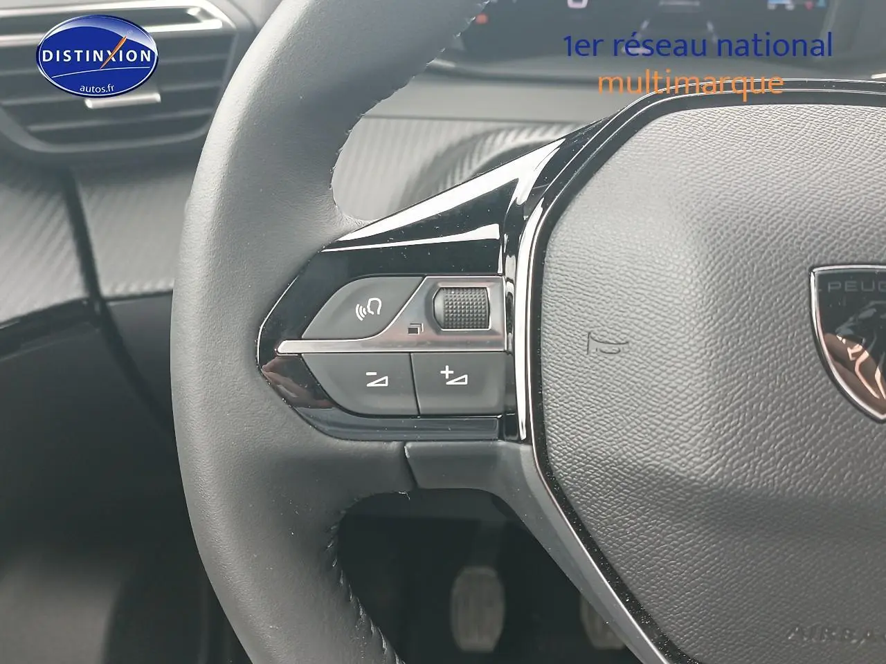 Gros plan sur le volant noir de la Peugeot 2008 1.2 100 allure, avec commandes intégrées côté gauche.