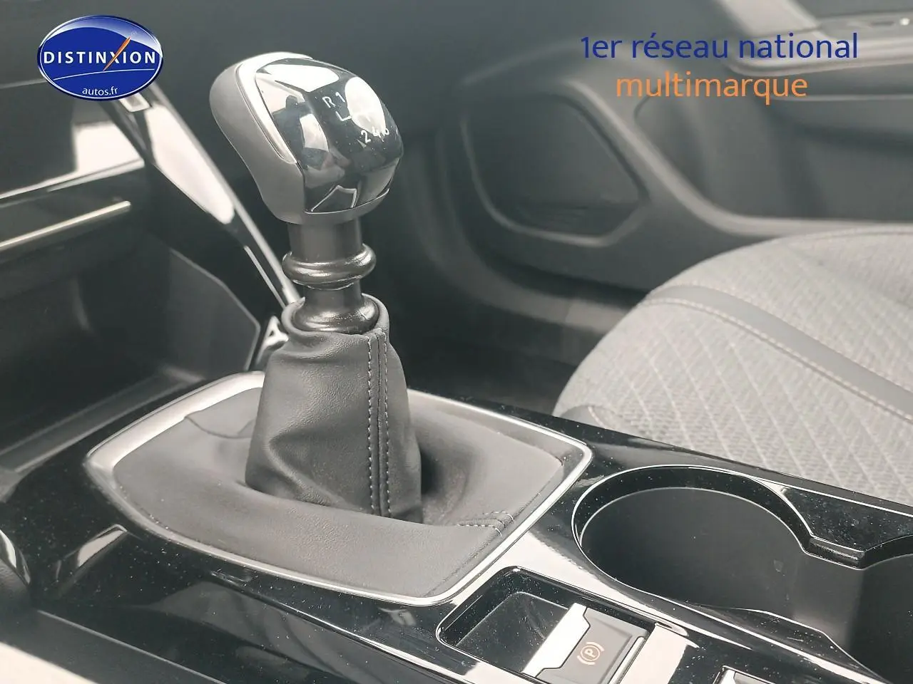 Gros plan sur la boîte manuelle et la console centrale noire avec porte-gobelet du Peugeot 2008 rouge elixir.