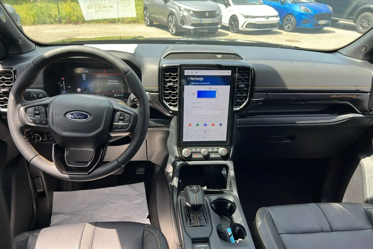 Vue intérieure du tableau de bord du Ford Ranger PHEV Wildtrak 2025 avec écran tactile vertical et volant cuir multifonctions.