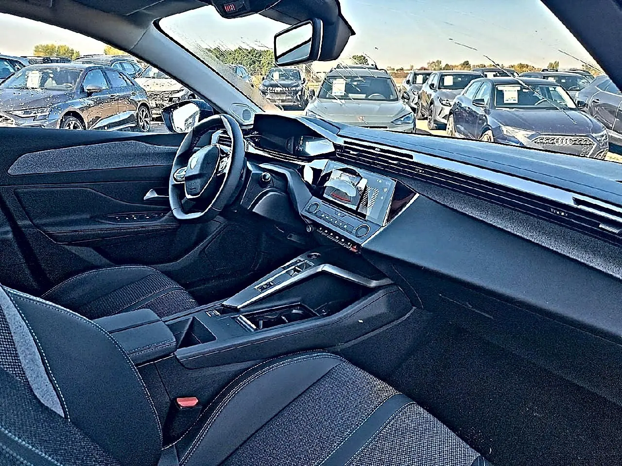 Vue intérieure côté conducteur de la Peugeot 308 SW 2025, montrant le tableau de bord moderne et la console centrale noire.