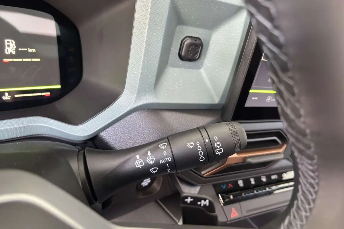 Gros plan sur la commande d’essuie-glace à gauche du volant dans l’habitacle gris du Dacia Bigster Hybrid-G 150 4x4.