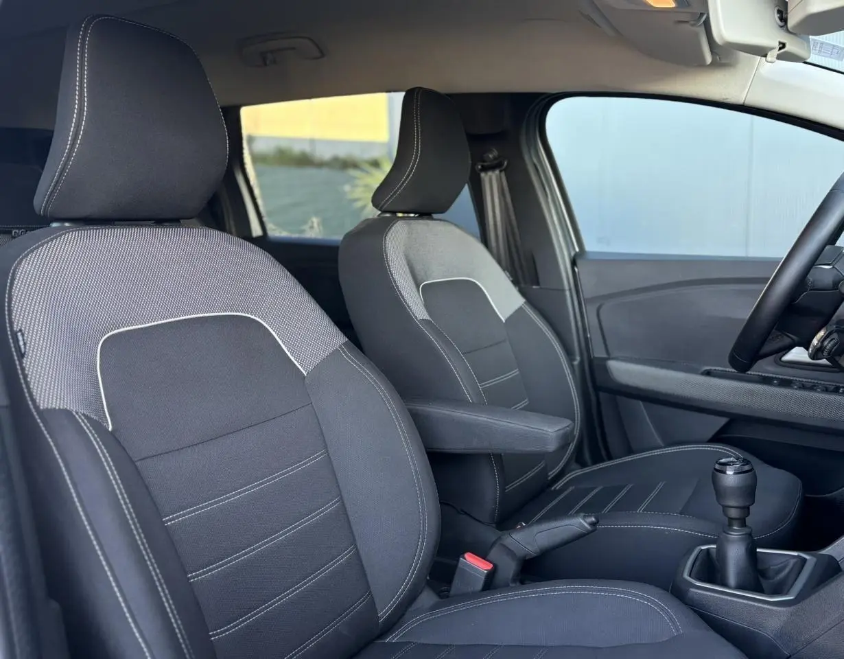 Vue intérieure côté droit du Dacia Jogger 2025, sièges noirs avec surpiqûres blanches et levier de vitesse manuel visible.