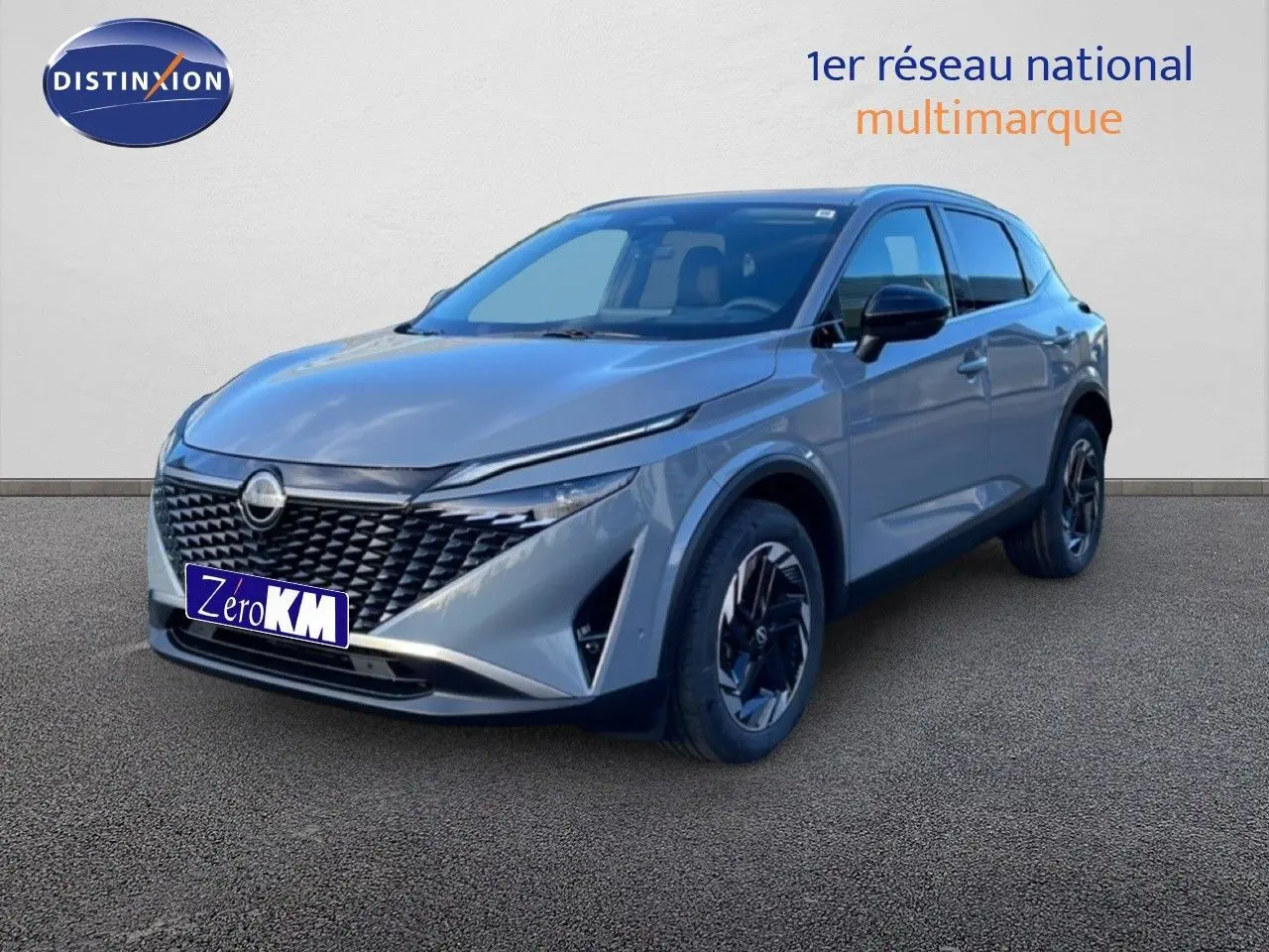 Vue 3/4 avant droit d'un Nissan Qashqai 2025 gris argile métallisé avec calandre noire et jantes foncées.