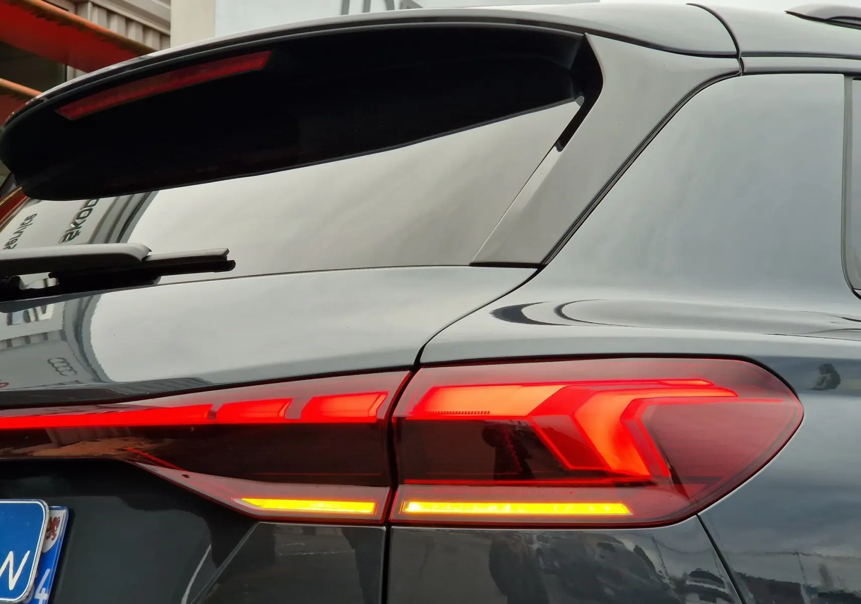 Gros plan sur le feu arrière droit rouge allumé de l'Audi Q6 e-tron Performance S-Line gris Manhattan 2025.