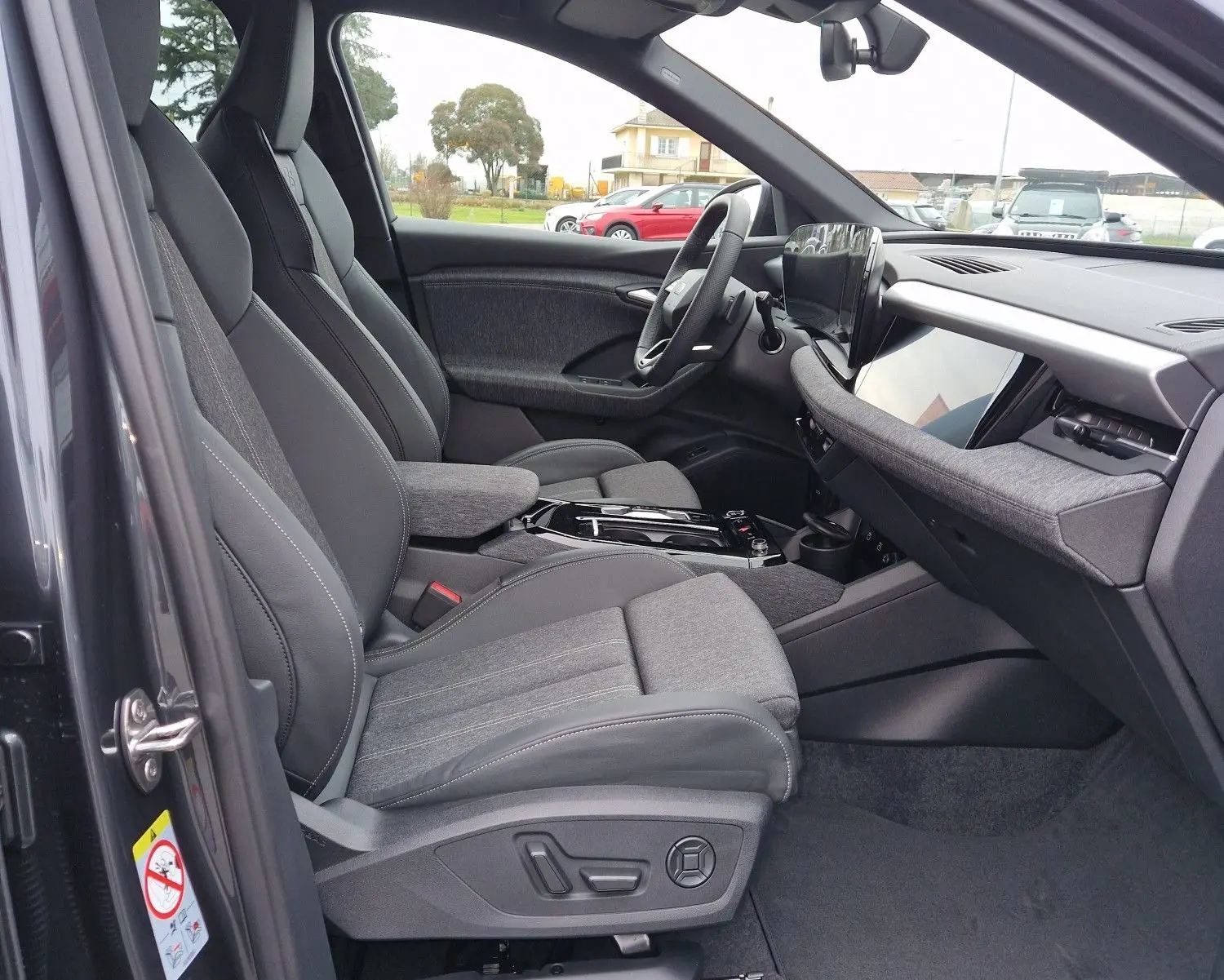 Vue intérieure côté conducteur de l'Audi Q6 e-tron Performance S-Line 2025, sièges gris et tableau de bord moderne.