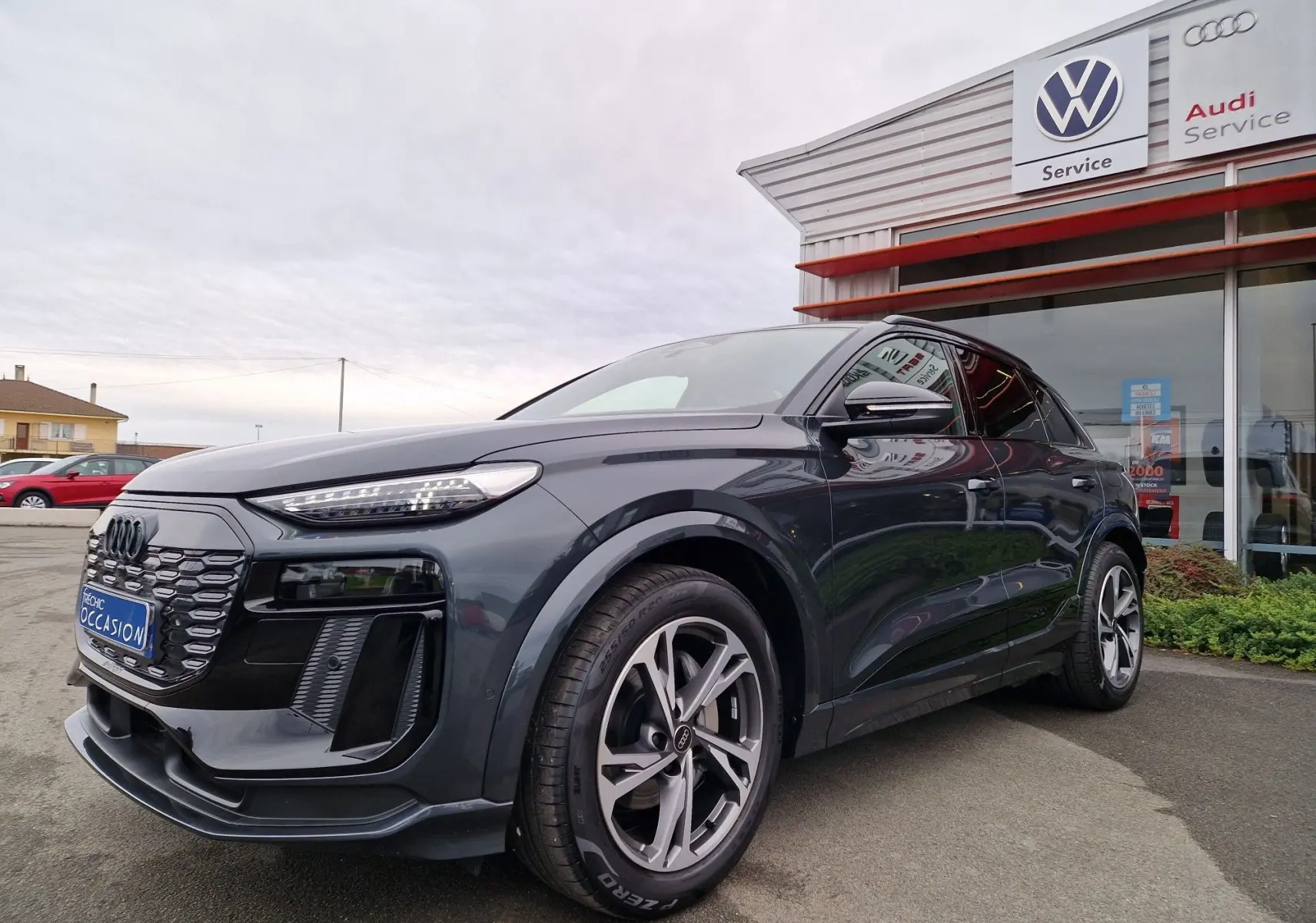 Audi Q6 e-tron Performance S-Line gris Manhattan, vue 3/4 avant mettant en valeur sa calandre et ses jantes distinctives.