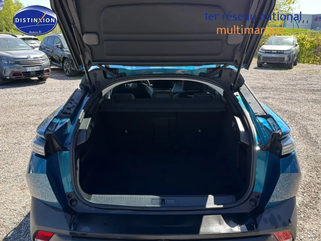 Vue arrière ouverte du coffre d'une Peugeot 408 Hybrid 145 allure bleu, montrant l'espace de chargement vide.