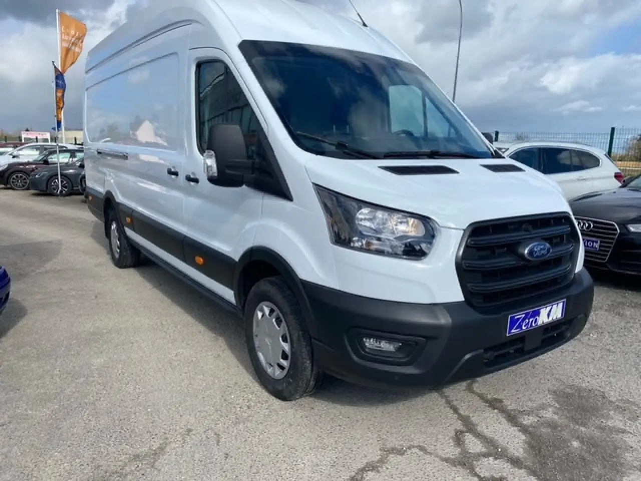 Ford Transit Fourgon blanc vu en 3/4 avant droit, avec calandre noire et pare-chocs avant noir mat.