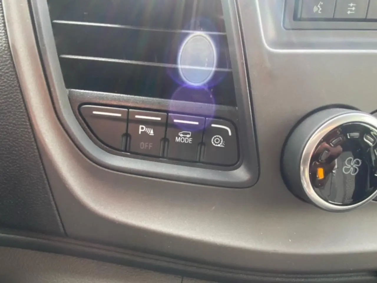 Gros plan sur les commandes de bord noires du Ford Transit Fourgon blanc, avec boutons d’aide au stationnement et mode conduite.