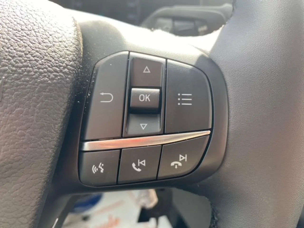 Gros plan sur les commandes multifonctions au volant du Ford Transit Fourgon blanc, côté gauche.