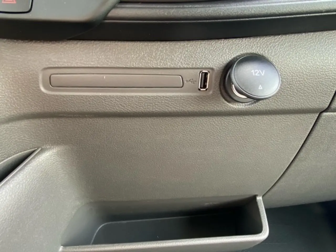 Gros plan sur la console centrale grise du Ford Transit Fourgon 2023, avec prise USB et prise 12V visibles.