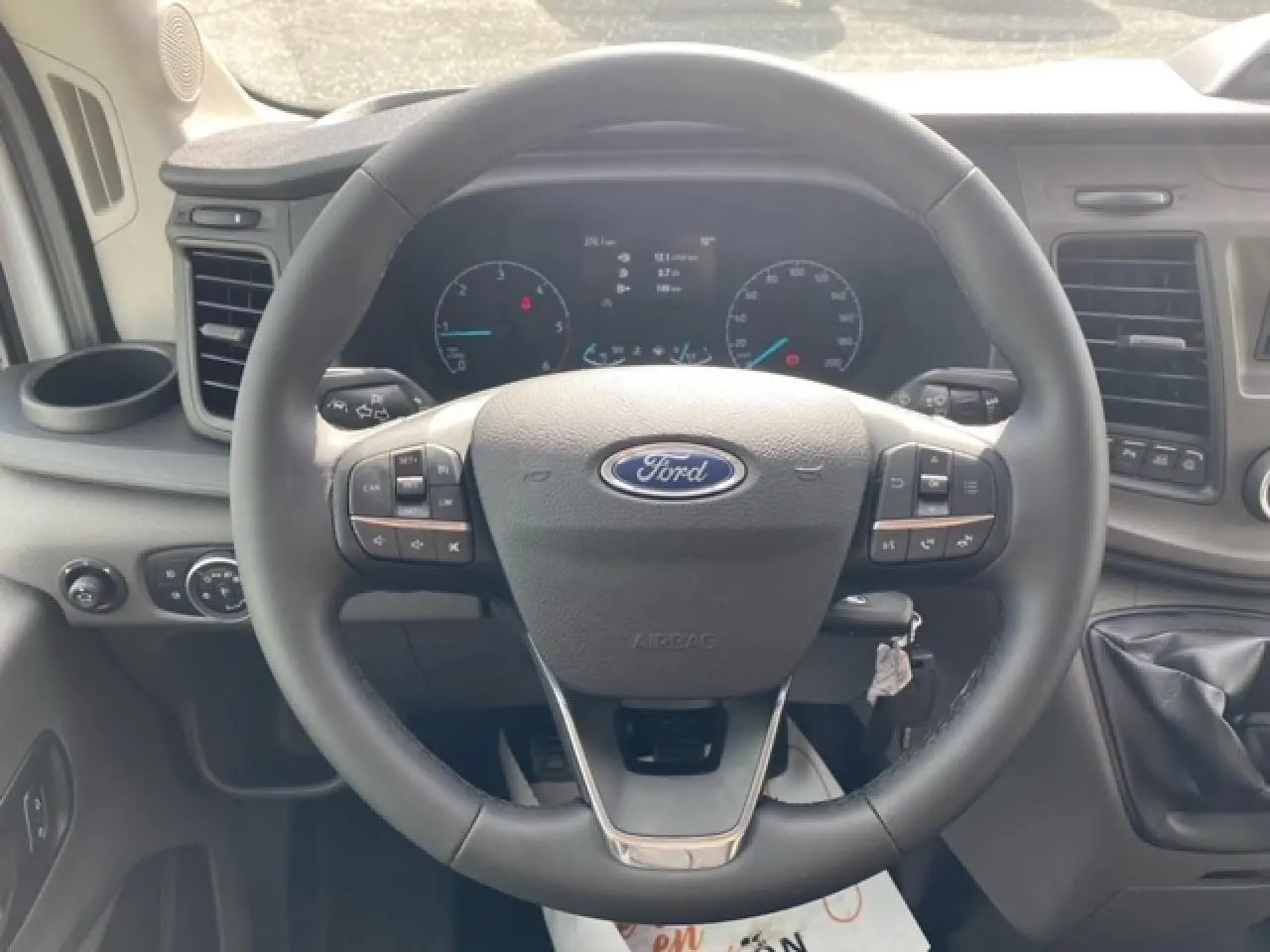 Vue intérieure centrée sur le volant multifonction du Ford Transit Fourgon 2023 avec tableau de bord numérique.