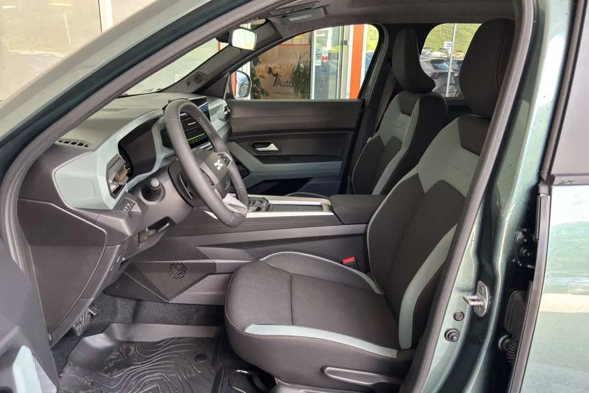 Vue intérieure côté conducteur du Dacia Bigster vert cèdre, avec sièges bi-ton et tableau de bord digital.