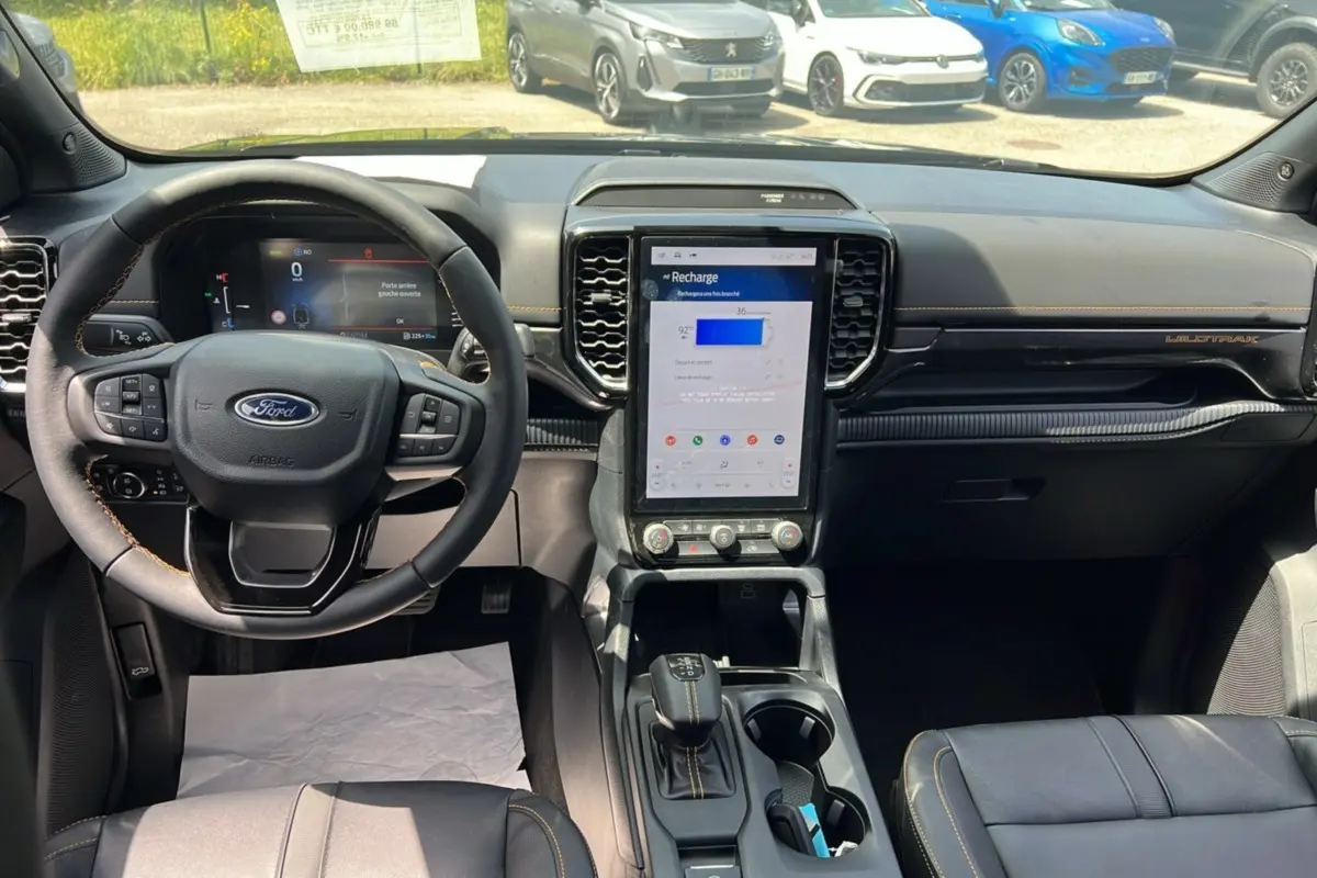 Intérieur du Ford Ranger Wildtrak 2025 noir agate, vue frontale sur le tableau de bord avec écran tactile vertical et volant multifonction.