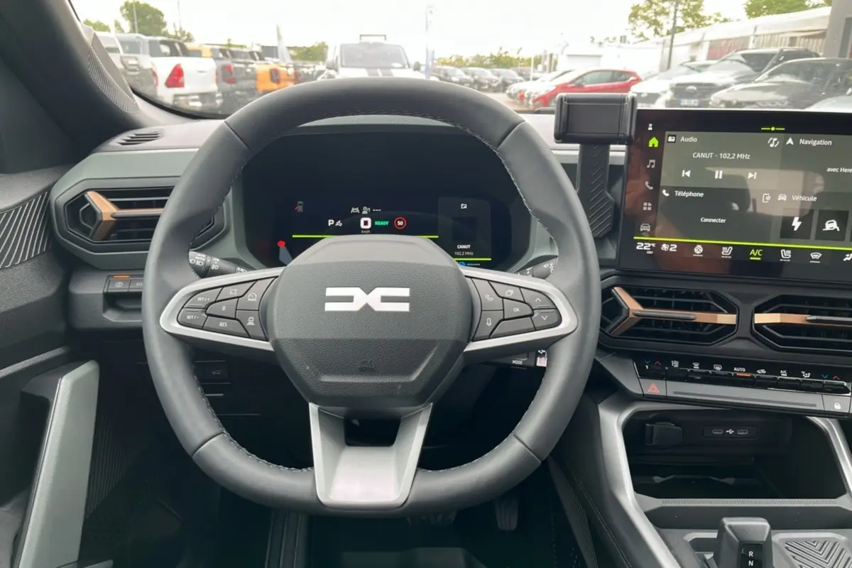 Vue intérieure centrée sur le volant cuir et le tableau de bord digital du Dacia Bigster Hybrid 155 Extreme Plus.