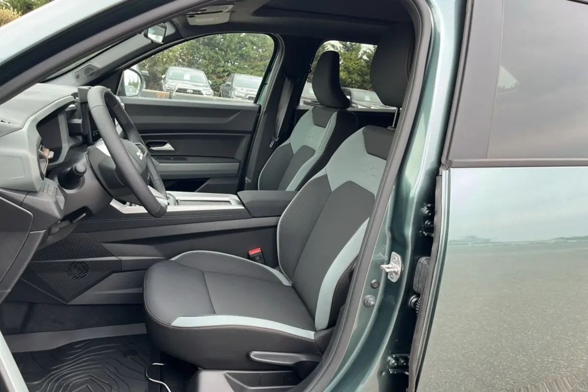 Intérieur côté conducteur du Dacia Bigster vert cèdre 2025, sièges bi-ton et tableau de bord moderne visible.