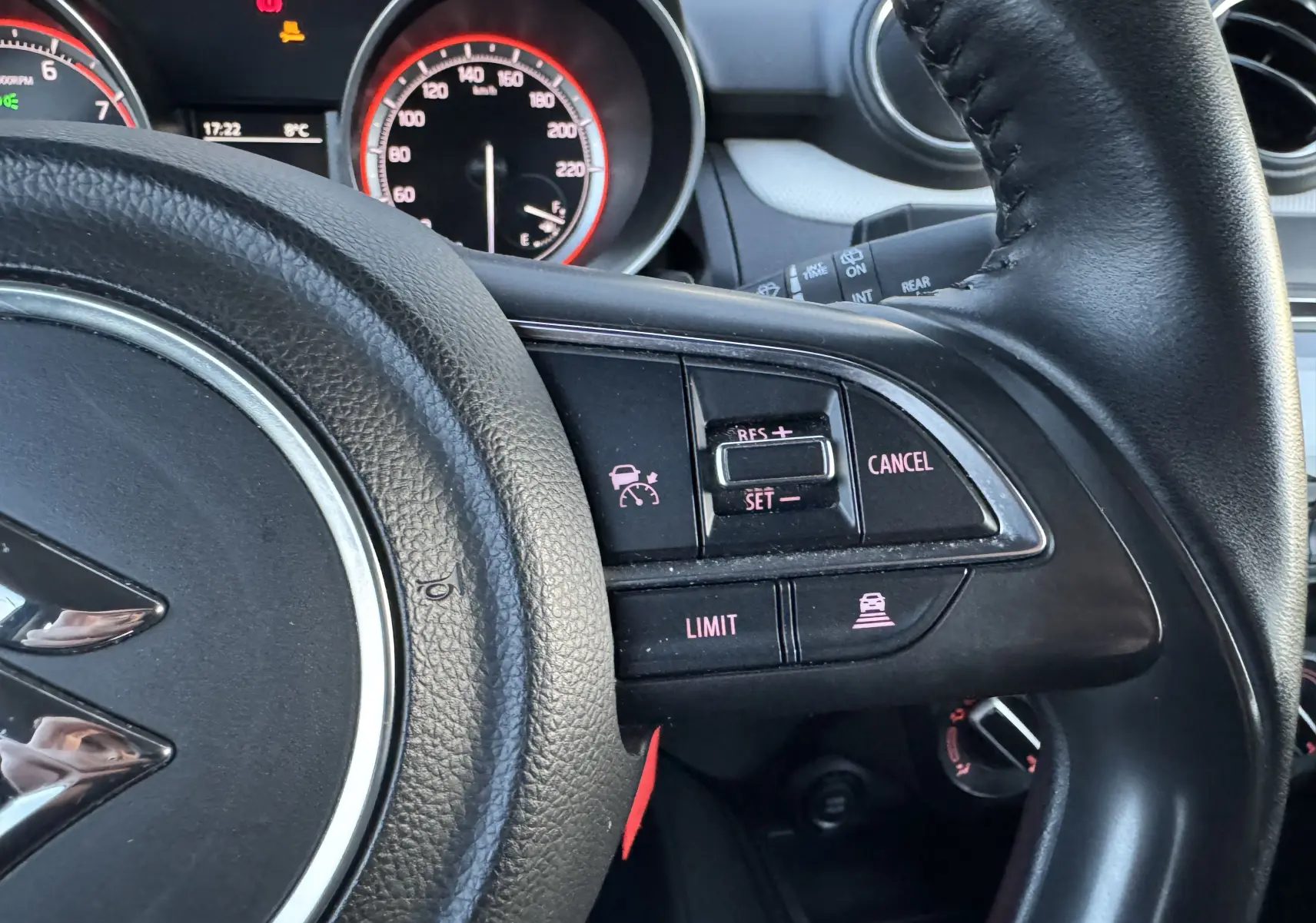 Vue rapprochée du volant noir de la Suzuki Swift 1.2 Dualjet Hybrid 2021, montrant les commandes de régulateur de vitesse.