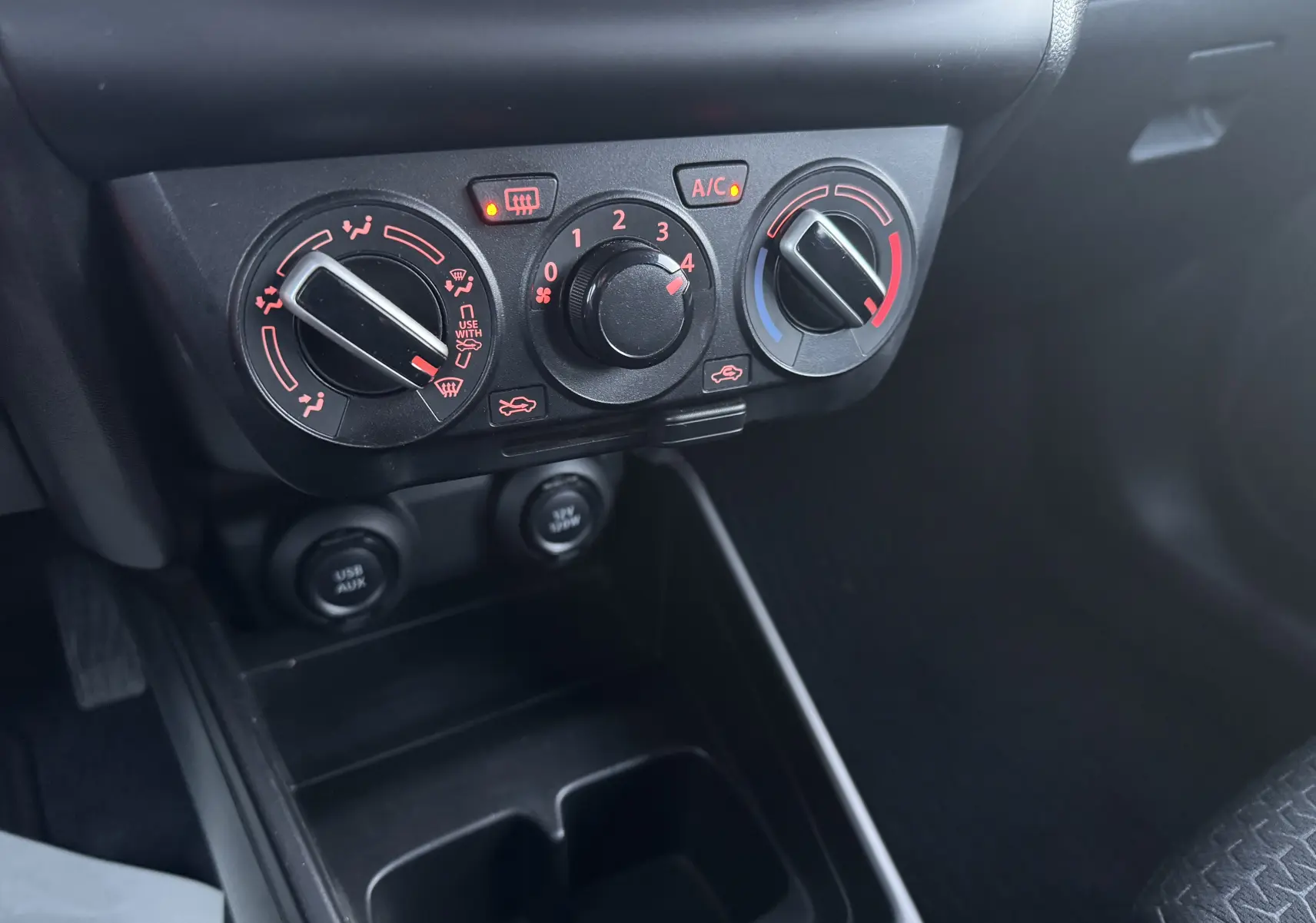 Gros plan sur les commandes de climatisation et ventilation noires du tableau de bord de la Suzuki Swift gris 2021.