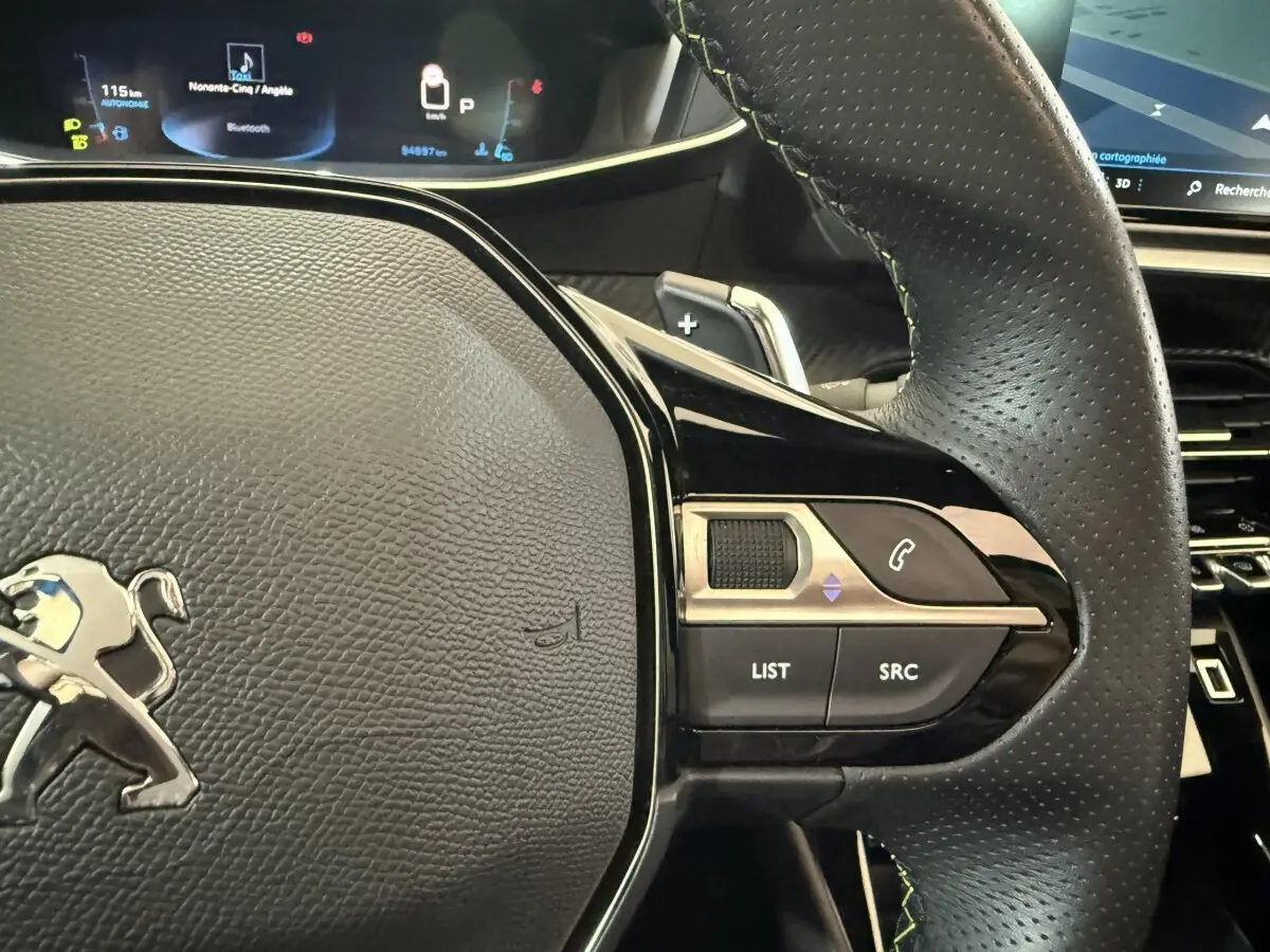 Gros plan sur le volant cuir perforé côté droit du Peugeot 2008 GT Pack 2021 avec commandes audio et écran numérique en arrière-plan.