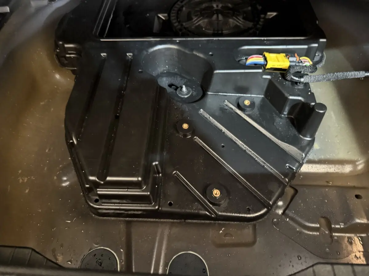 Vue rapprochée du compartiment de rangement sous le plancher du coffre du Peugeot 2008 bleu, avec câblage visible.