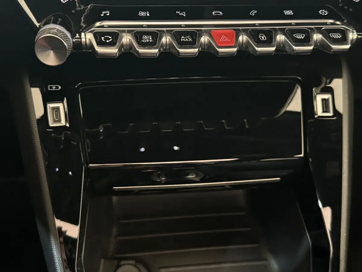 Gros plan sur la console centrale noire brillante du Peugeot 2008 GT Pack 2021 avec boutons de commande et ports USB.